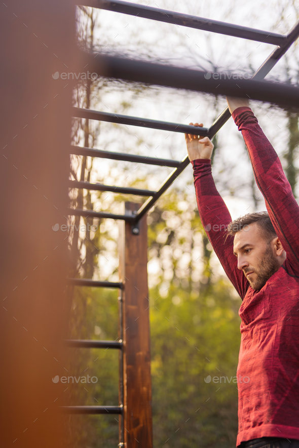 Man doing pull ups while working out in street workout park Stock Photo